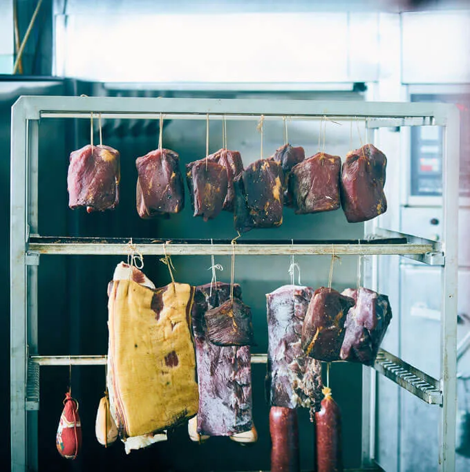 Reiferegal mit hängendem Schinken, Speck und Würsten in der Metzgerei